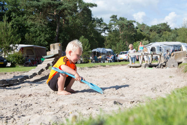 kind speelt met zand in kampeer gebied