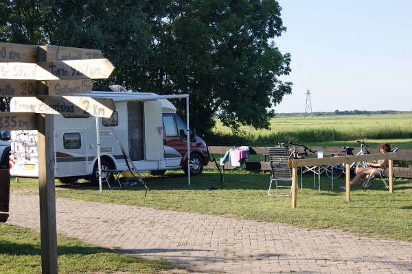 Vrouw zit in de zon bij haar camper